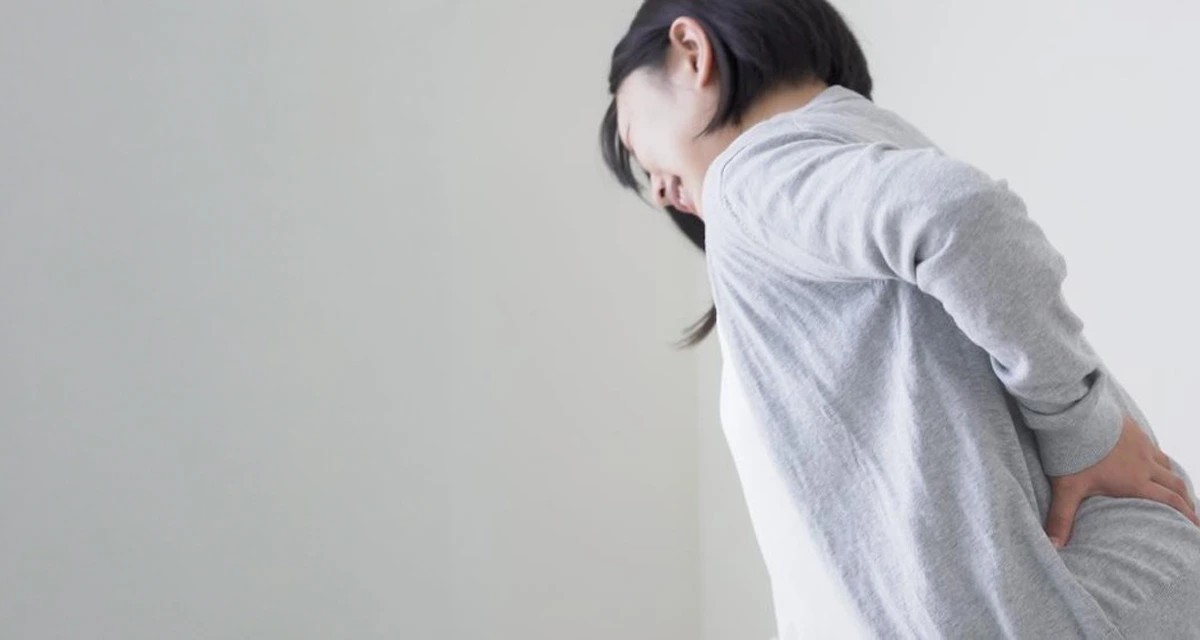腰の痛みで体を支える女性